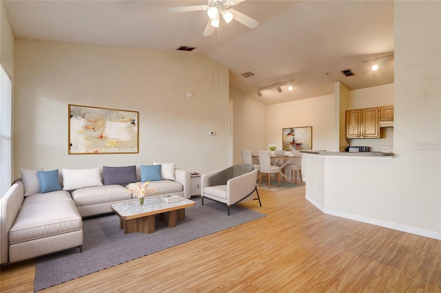 living room featuring lofted ceiling, track lighting, ceiling fan, and light hardwood / wood-style flooring