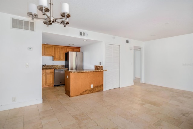 kitchen featuring appliances with stainless steel finishes, kitchen peninsula, a notable chandelier, pendant lighting, and light stone countertops