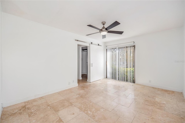 spare room featuring ceiling fan and a barn door