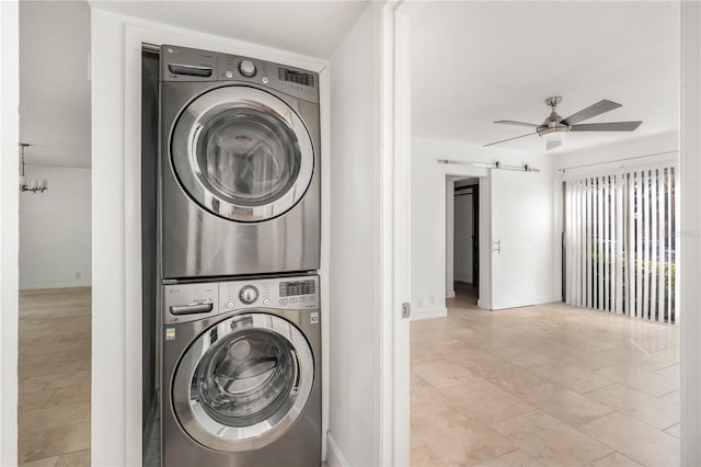 laundry area featuring stacked washer / drying machine, a barn door, and ceiling fan