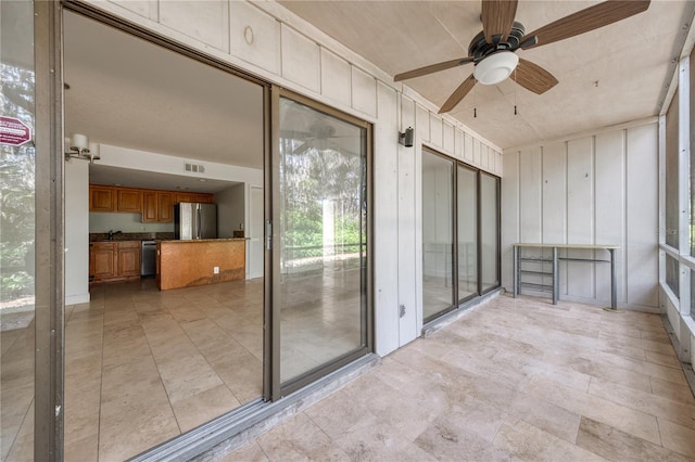 unfurnished sunroom featuring ceiling fan