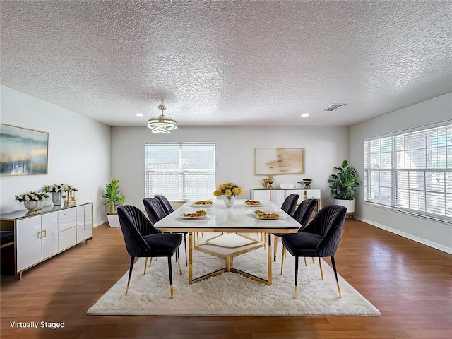 dining area featuring a wealth of natural light, a textured ceiling, and dark hardwood / wood-style flooring