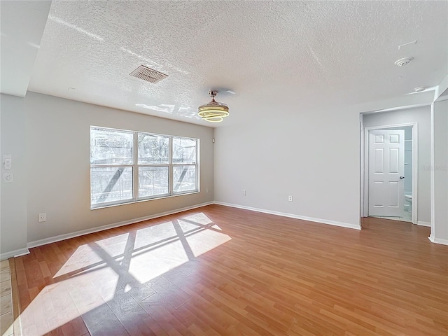 unfurnished room featuring wood-type flooring and a textured ceiling