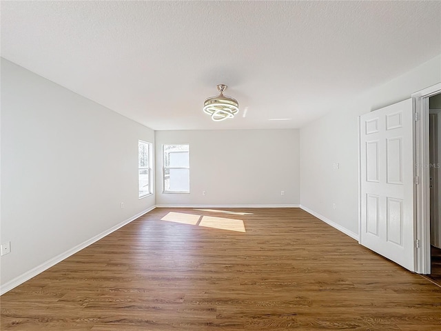 spare room featuring dark hardwood / wood-style flooring and a textured ceiling