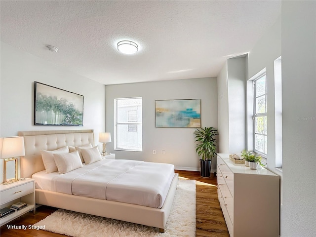 bedroom with dark wood-type flooring, multiple windows, and a textured ceiling