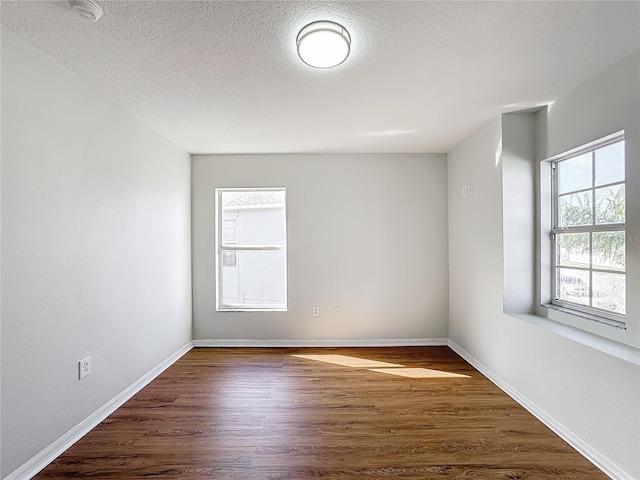 unfurnished room with dark hardwood / wood-style floors and a textured ceiling