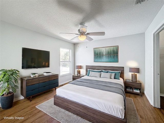 bedroom featuring hardwood / wood-style flooring, a textured ceiling, and ceiling fan