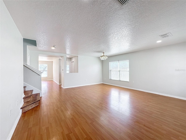 unfurnished living room featuring hardwood / wood-style floors and a textured ceiling