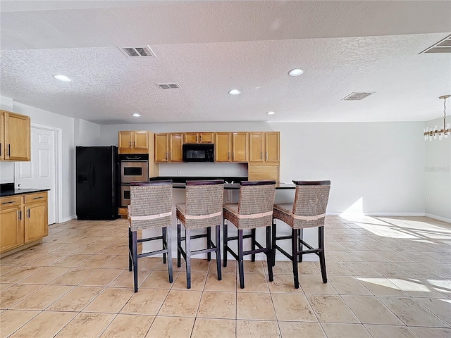 kitchen with a breakfast bar area, a textured ceiling, light tile patterned floors, and black appliances