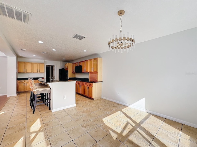 kitchen with light tile patterned floors, an inviting chandelier, hanging light fixtures, fridge, and a kitchen island