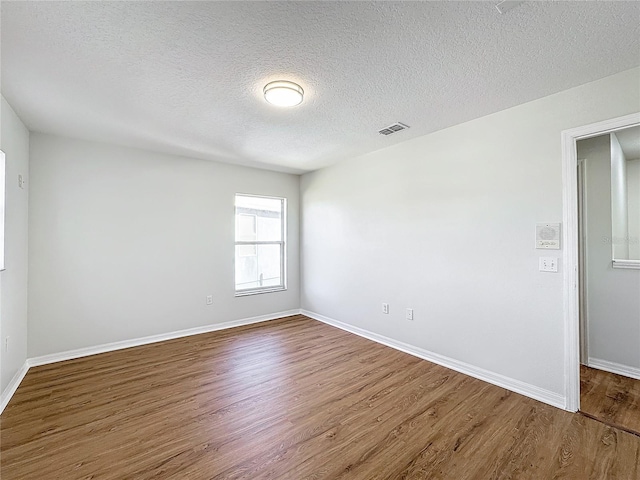 unfurnished room featuring hardwood / wood-style floors and a textured ceiling