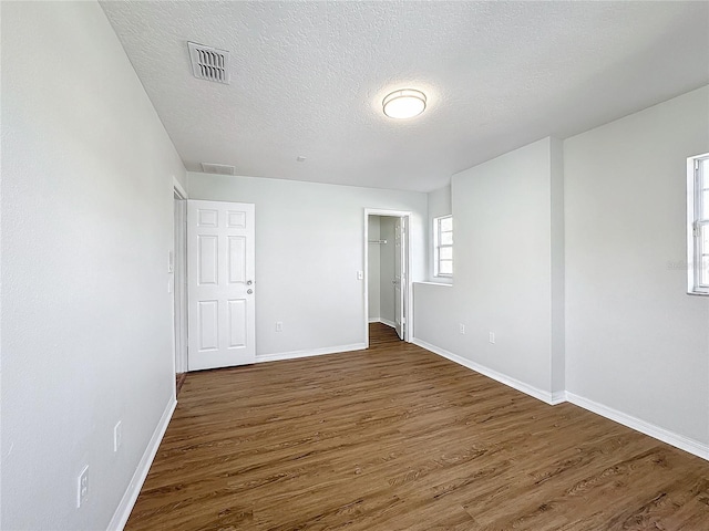 unfurnished bedroom with a textured ceiling and dark hardwood / wood-style flooring