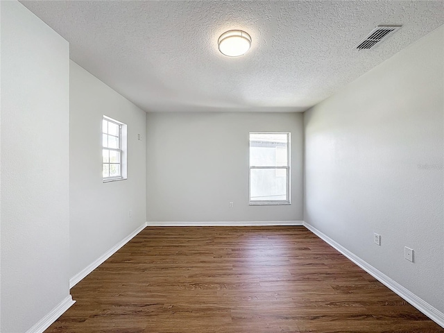 unfurnished room with dark hardwood / wood-style flooring and a textured ceiling