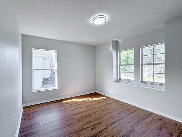 unfurnished room featuring dark wood-type flooring and a textured ceiling