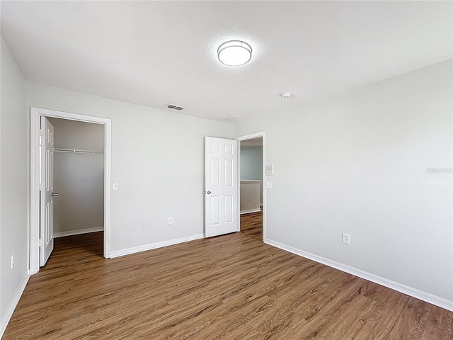 unfurnished bedroom with a walk in closet, dark hardwood / wood-style flooring, and a closet