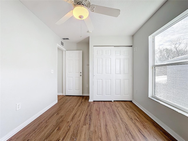 unfurnished bedroom with multiple windows, a closet, ceiling fan, and light hardwood / wood-style floors