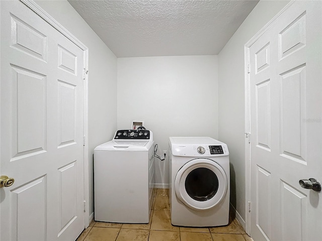 laundry room featuring light tile patterned flooring, a textured ceiling, and washer and clothes dryer