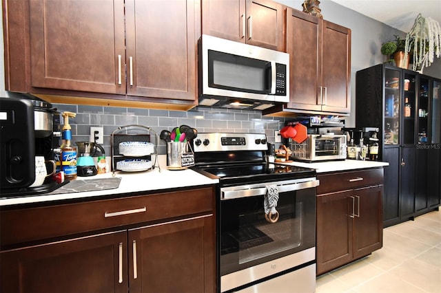 kitchen featuring tasteful backsplash, light tile patterned floors, stainless steel appliances, and dark brown cabinetry