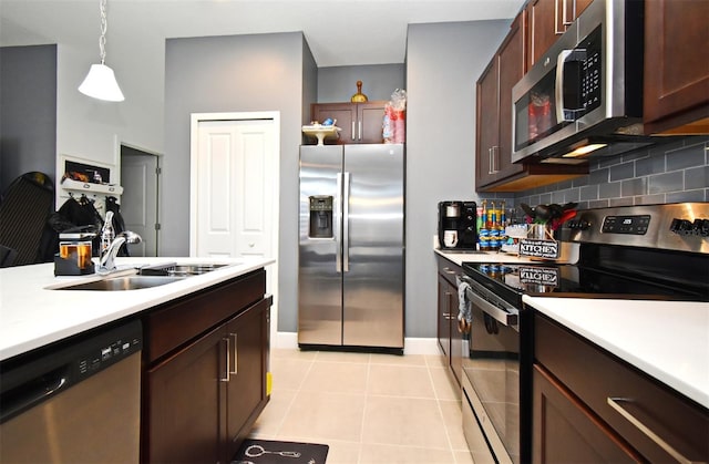 kitchen featuring sink, light tile patterned floors, hanging light fixtures, stainless steel appliances, and decorative backsplash