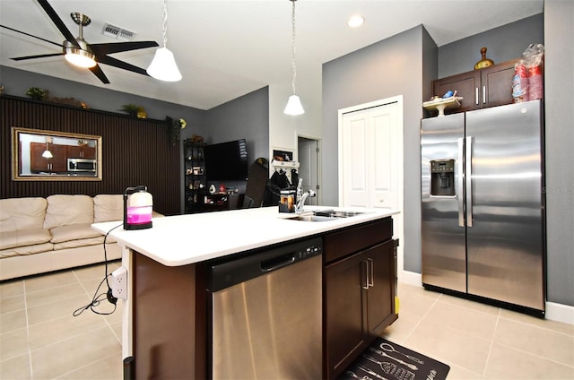 kitchen with appliances with stainless steel finishes, sink, a kitchen island with sink, light tile patterned floors, and dark brown cabinets