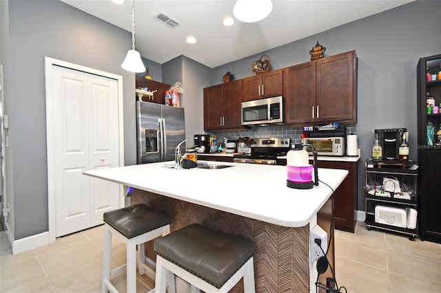 kitchen featuring stainless steel appliances, sink, light tile patterned floors, and decorative light fixtures