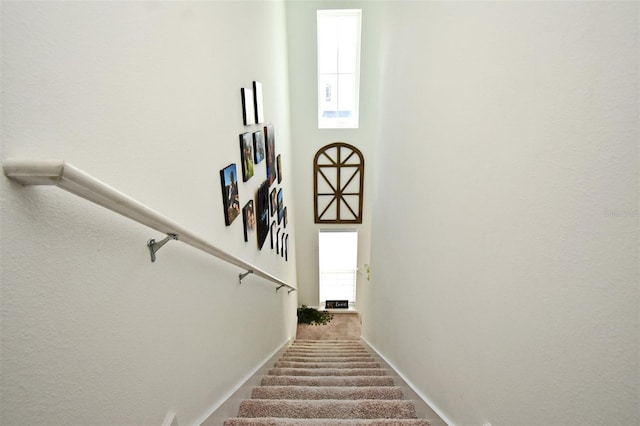 staircase with a towering ceiling and carpet flooring