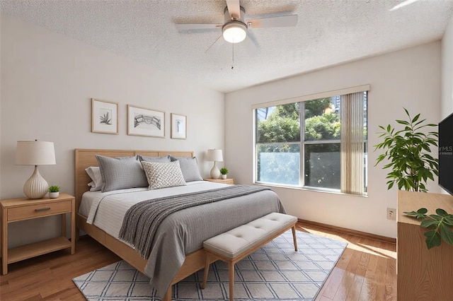 bedroom with hardwood / wood-style flooring, a textured ceiling, and ceiling fan