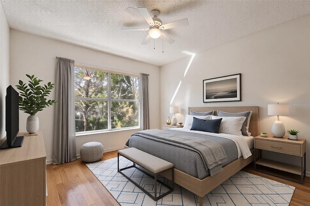 bedroom featuring a textured ceiling, light hardwood / wood-style floors, and ceiling fan