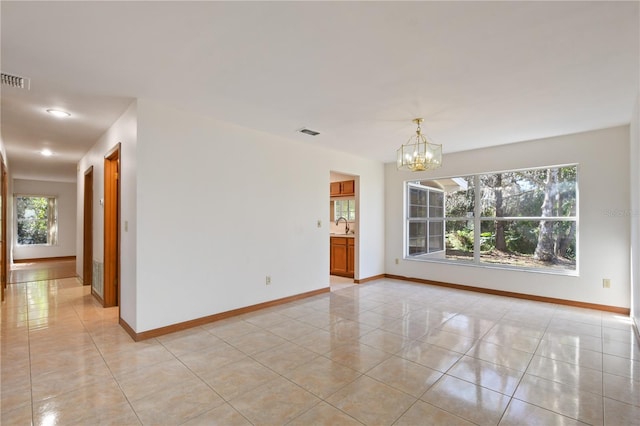 unfurnished room featuring light tile patterned flooring, a chandelier, and sink