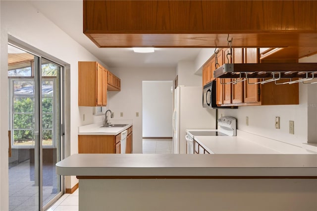 kitchen featuring white appliances, kitchen peninsula, sink, and light tile patterned floors