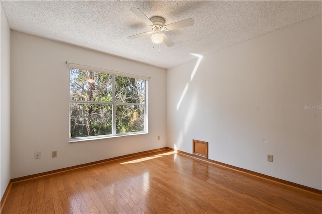 empty room featuring hardwood / wood-style flooring, a textured ceiling, and ceiling fan