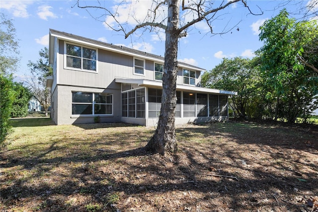 back of house with a sunroom and a lawn