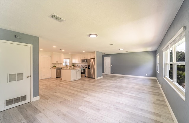 unfurnished living room featuring sink, light hardwood / wood-style flooring, and a textured ceiling