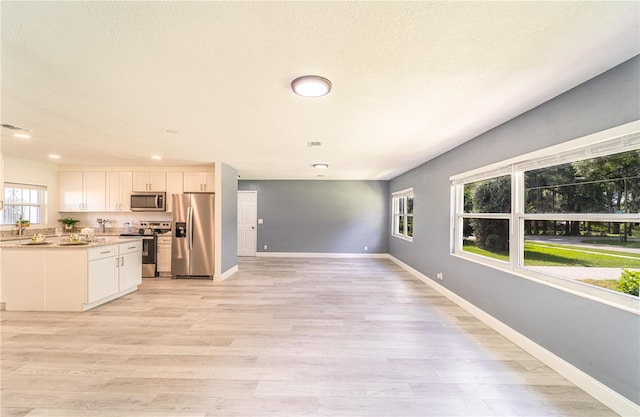 kitchen featuring white cabinetry, a healthy amount of sunlight, stainless steel appliances, and light hardwood / wood-style floors