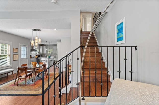 stairway with wood-type flooring and a textured ceiling