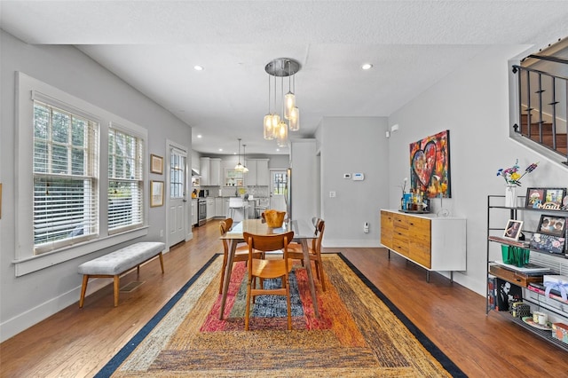 dining room with hardwood / wood-style flooring, a textured ceiling, and a notable chandelier