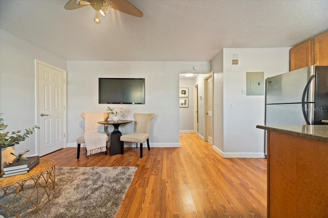 interior space featuring electric panel, stainless steel fridge, ceiling fan, and light hardwood / wood-style flooring