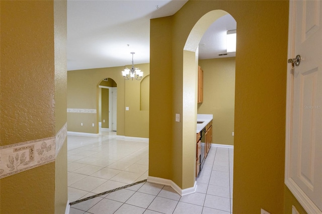 hallway with an inviting chandelier and light tile patterned floors