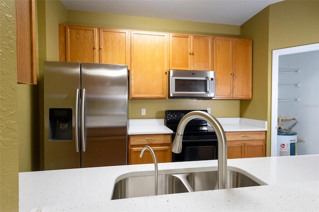 kitchen featuring light stone counters, stainless steel appliances, and sink