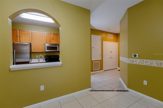 kitchen featuring light tile patterned flooring, appliances with stainless steel finishes, and sink