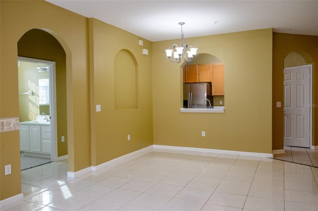 unfurnished room with light tile patterned flooring, sink, and an inviting chandelier