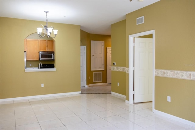 empty room with an inviting chandelier and light tile patterned floors