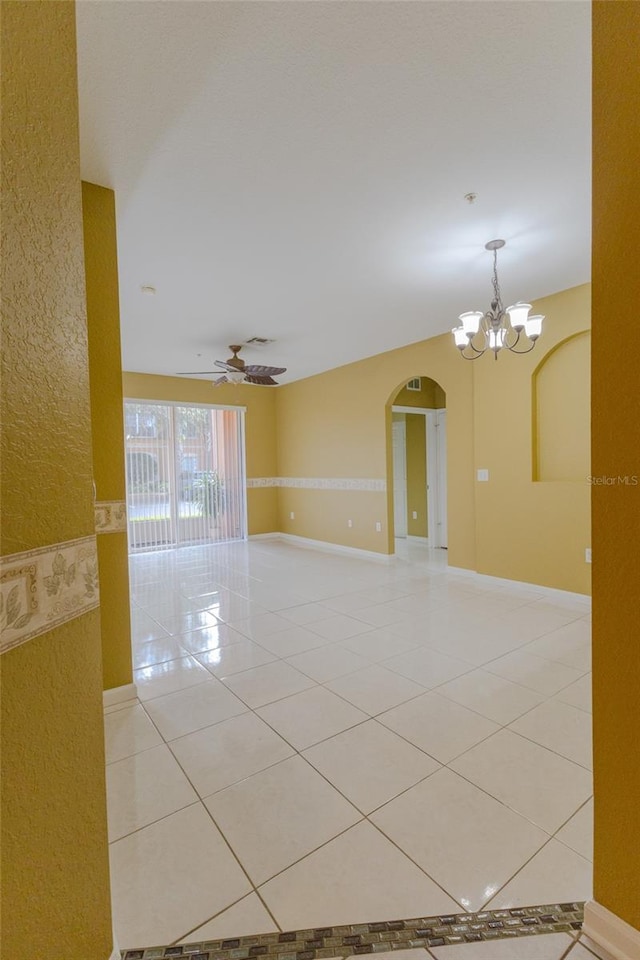 tiled empty room with ceiling fan with notable chandelier