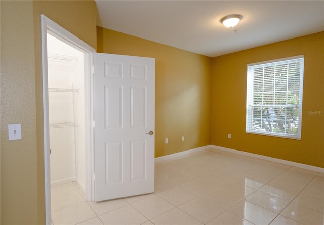 unfurnished bedroom featuring a walk in closet, a closet, and light tile patterned floors