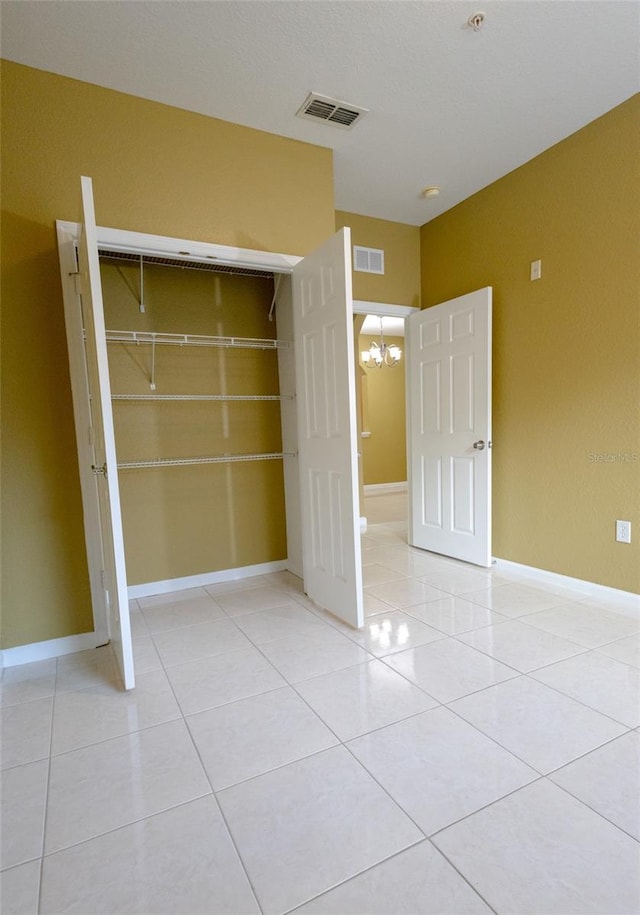 spare room featuring light tile patterned flooring and a chandelier