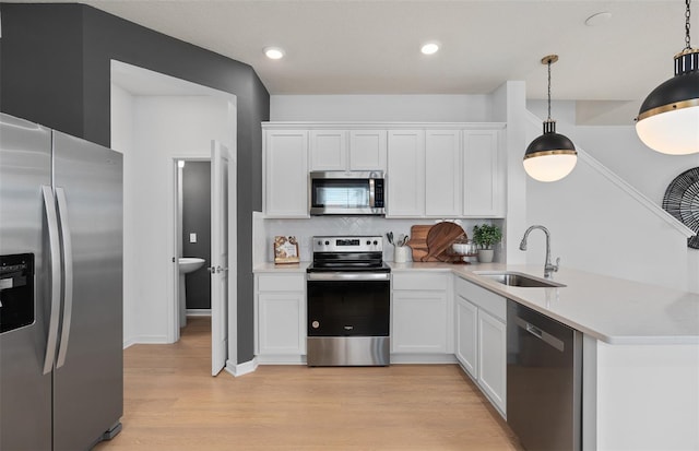 kitchen with sink, white cabinetry, hanging light fixtures, stainless steel appliances, and decorative backsplash