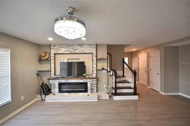 unfurnished living room with wood-type flooring, a fireplace, and an inviting chandelier