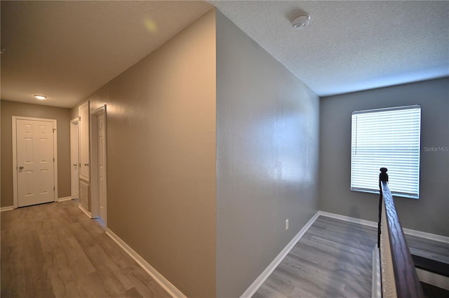 hallway with light hardwood / wood-style flooring and a textured ceiling