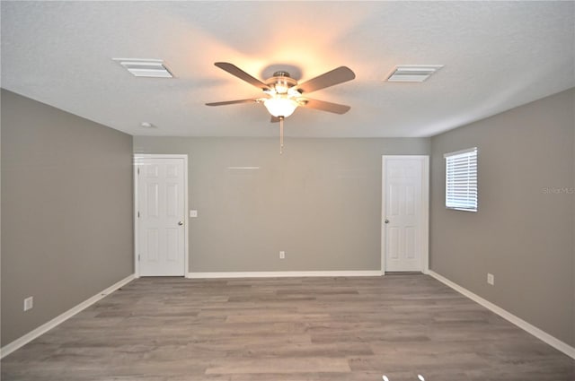 unfurnished room featuring ceiling fan, hardwood / wood-style flooring, and a textured ceiling