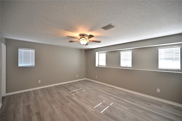 empty room featuring ceiling fan, wood-type flooring, and a textured ceiling